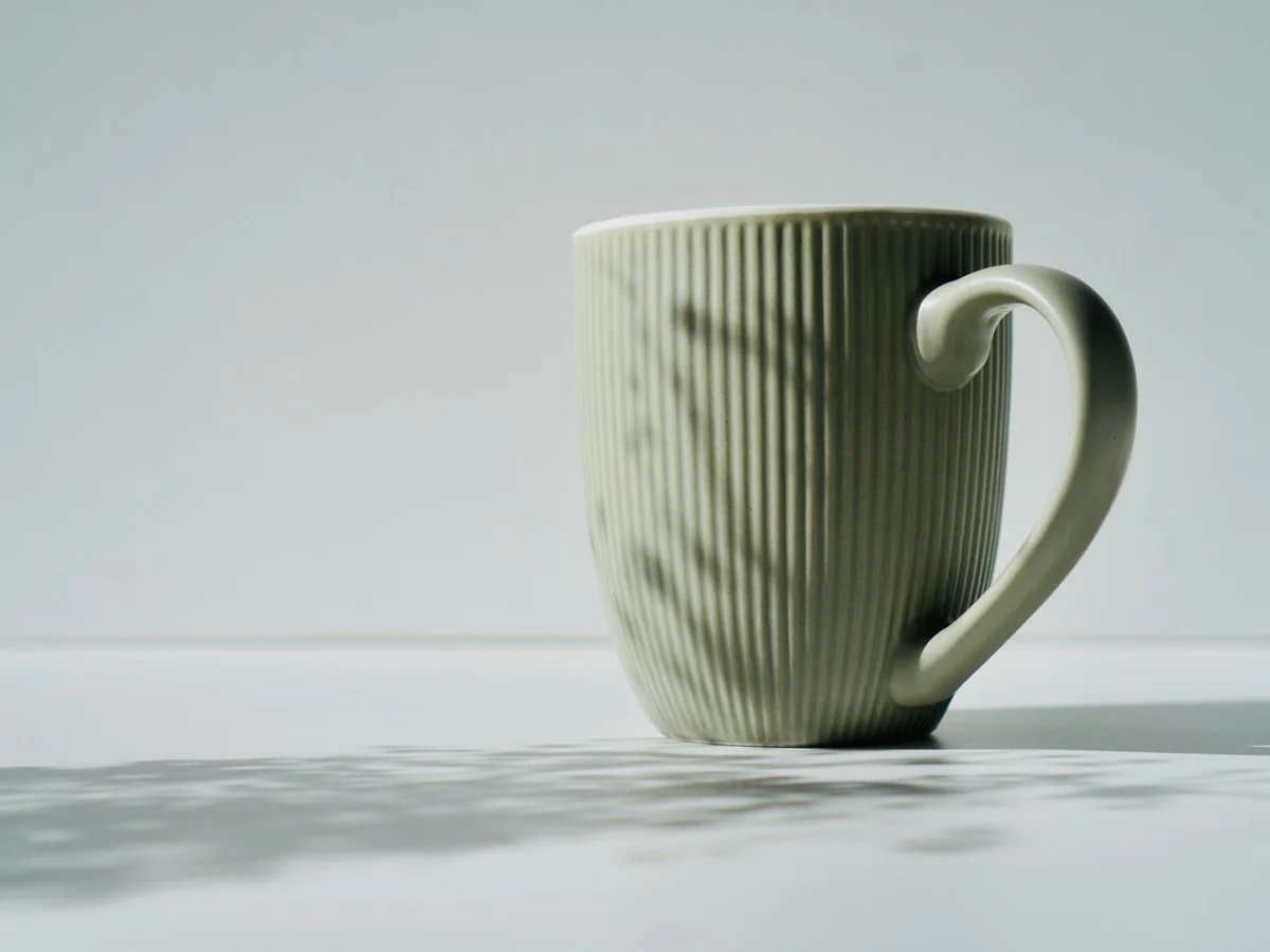 A ribbed ceramic mug with a large curved handle in side view.