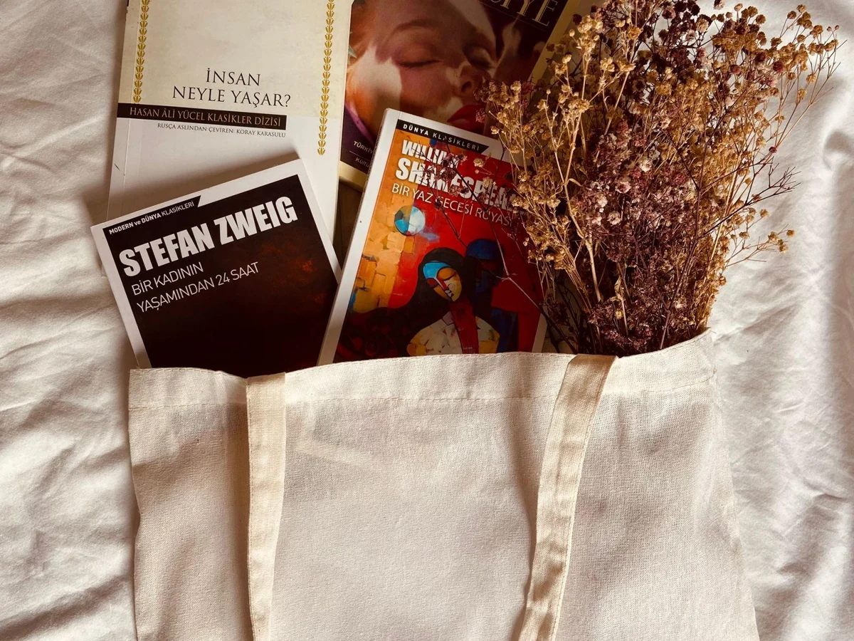 A natural canvas tote with several books arranged at its opening.