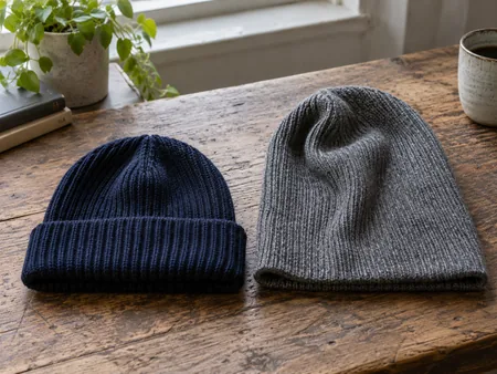 Two plain rib-knit beanies laid side by side, a compact folded-cuff beanie and a longer slouchy beanie.