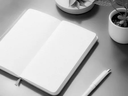 An open plain notebook with a pen on a desk.