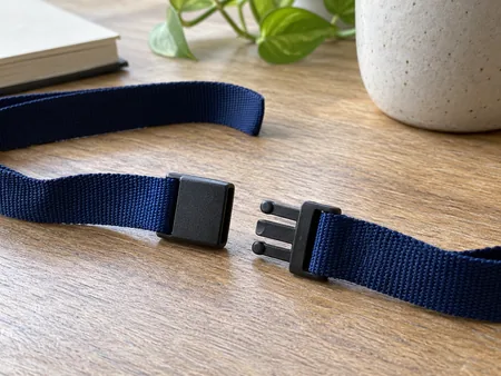 Close-up of a plain woven lanyard on a tabletop with its plastic breakaway safety connector separated into two halves.