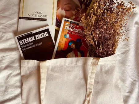 A natural canvas tote with several books arranged at its opening.