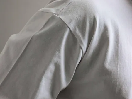 Close view of a white T-shirt shoulder and sleeve seam.